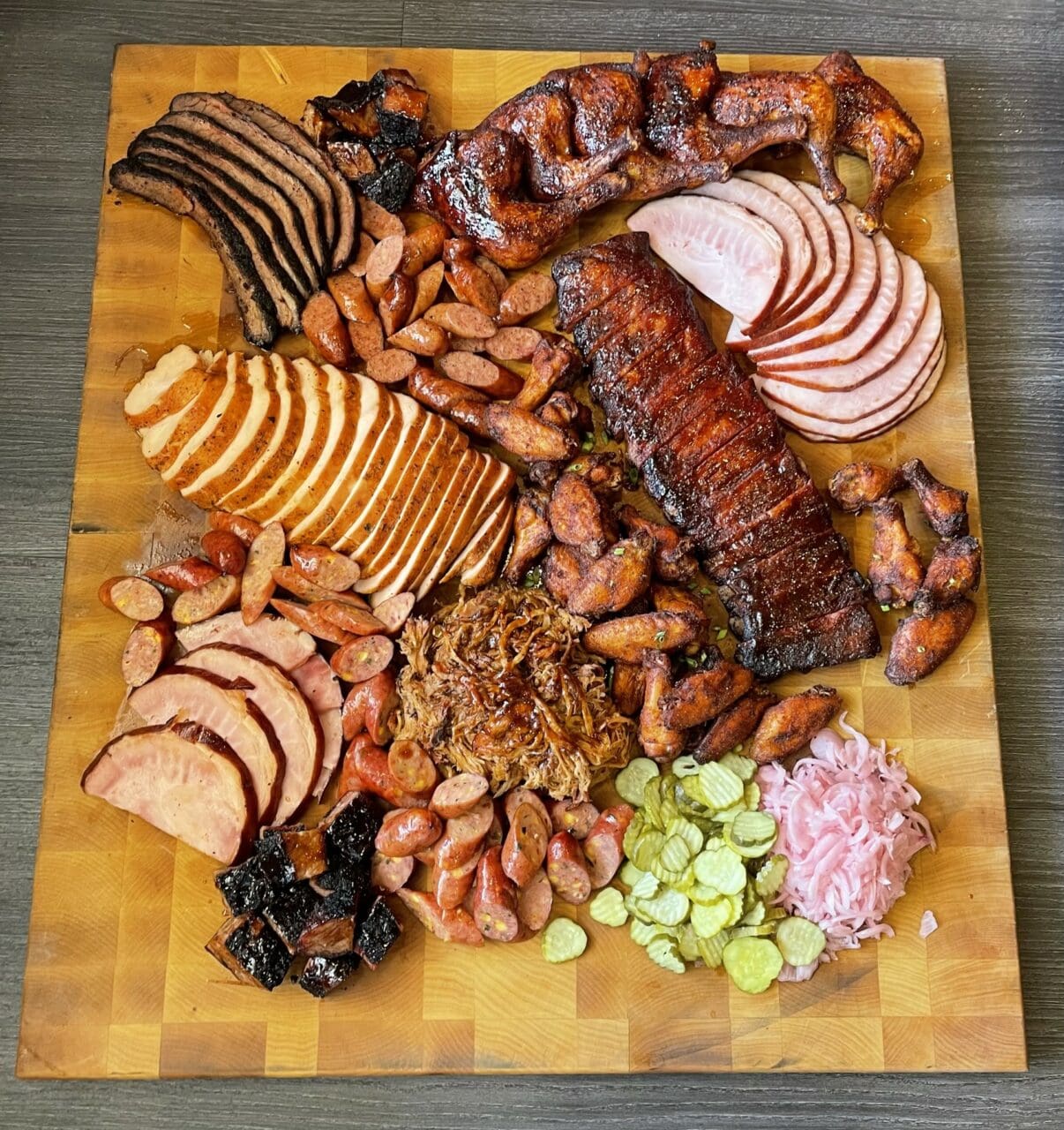 a butcher block full of smoked meats and bbq