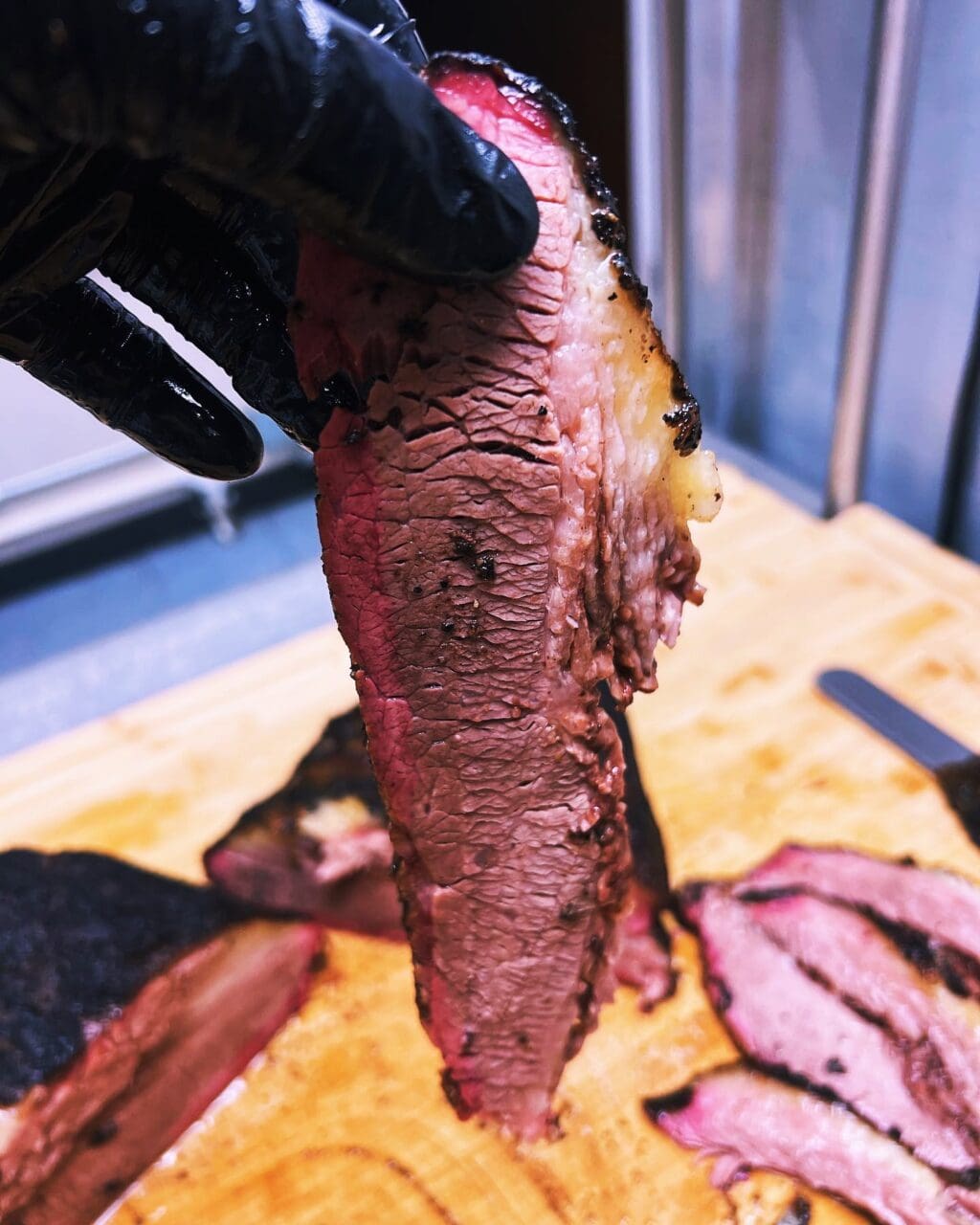 a slice of smoked brisket being held in a hand.